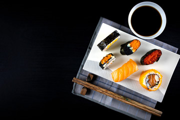 Assorted sushi set on black wooden table background. Space for text. Japanese sushi. Top view. Sushi nigiri. Japanese dinner/lunch. Food frame. Different sushi mixed.