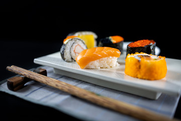 Assorted sushi set on black wooden table background. Space for text. Japanese sushi. 45 degree angle view and close up shot. Sushi nigiri. Japanese dinner/lunch. Food frame. Different sushi mixed.