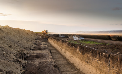 Crane digging a channel for gas pipeline