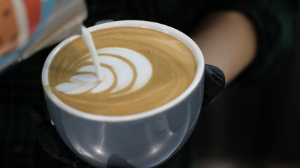 Barista at work. The process of making coffee and cacao. A glass of foaming milk. Electric Grinder Grinds Coffee Beans In Filter Holder.