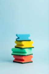 Colored sponges for washing dishes on a blue background. Cleanliness and cleaning concept