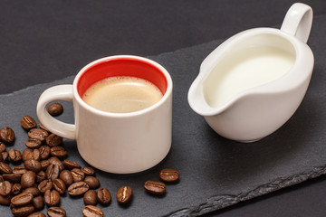 Cup of coffee and coffee beans on black background.