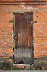 Old wooden door with padlock in brick wall, soft focus.