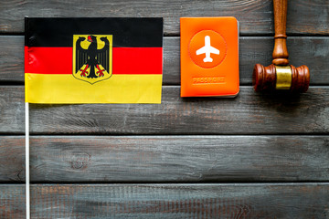 Visa to German concept. Germany flag near passport and judge hammer on dark wooden background top-down copy space
