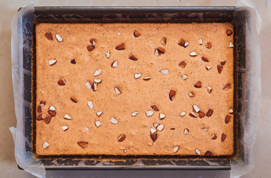 Close Up Of Cinnamon Spice And Almond Dry Cake Flat Lay Image. Small Bakery Homemade Cake In A Baking Paper Sheet. Full Cake Loaf In A Metal Pan. Website And Advertisement Pamphlet Background Image.