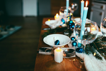 Table served for winter dinner in living room. Close up view, table setting. Christmas and winter decorations in blue colors. Beautiful served table with decorations