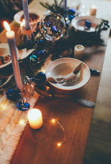 Table served for winter dinner in living room. Close up view, table setting. Christmas and winter decorations in blue colors. Beautiful served table with decorations
