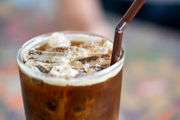 cold latte coffee close-up with a straw on a blurred background.