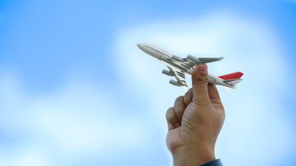 Young asian holding miniature toy airplane flying on cloud blue sky background. Travel and trip at summer by airplane with copy space