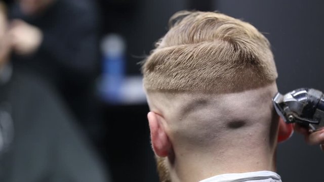 The man at the hairdresser cuts his hair. Haircut clipper close-up.