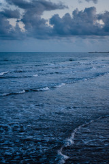 Evening beach at Cape Greco. Sea with waves and sky in clouds. Cyprus