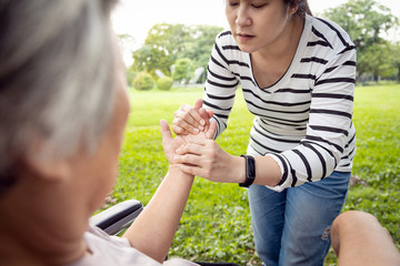 Fototapeta premium Asian daughter massaging palm and fingers of senior mother,elderly people having heumatoid arthritis, beriberi,peripheral neuropathies,old woman in wheelchair suffer from hand numbness or muscle pain