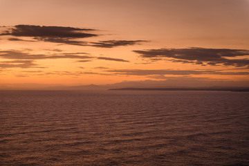Sunset in Cyprus, Cape Greco. Calm dark sea and orange sky with clouds