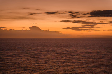 Wonderful sunset in Cyprus, Cape Greco. Calm dark sea and orange sky with clouds