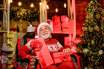 Obraz na płótnie Canvas Traditions concept. Legend about Santa Claus. Merry christmas. Elderly grandpa at home. Delivering gifts. Presents for family. Santa Claus relaxing in arm chair. Bearded senior man Santa Claus