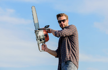 Sharp blade. Handsome man with chainsaw blue sky background. Gardener lumberjack equipment....