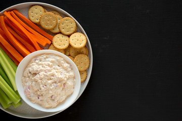 Homemade Pimento Cheese Dip with carrots, celery and crackers over black background, top view. Flat...
