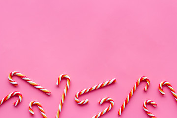 Christmas candies frame - cane with red and white stripes - on pink background top-down copy space