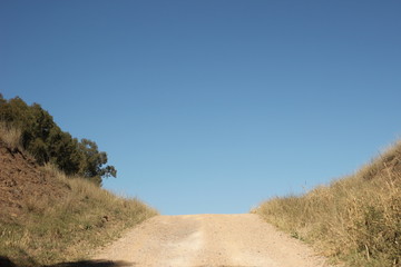 wide shot of long dirt dusty country road leading off into the distance on dry arid drought stricken agricultural farm land, rural New South Wales, Australia