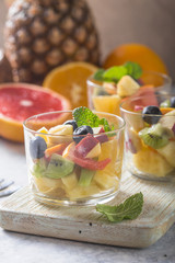Fruit salad in glasses,  fresh summer foods , healthy organic orange kiwi blueberries pineapple coconut. top view