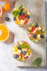 Fruit salad in glasses,  fresh summer foods , healthy organic orange kiwi blueberries pineapple coconut. top view
