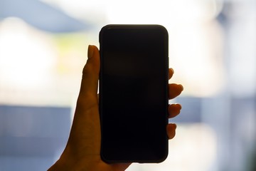 Woman hand holding cellphone on blurry background