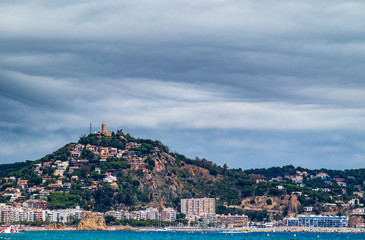 Obraz premium Blanes Castle, from the beach, with clouds threatening rain
