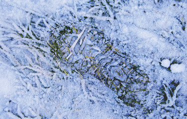 Footprints on shoes on snowy grass.