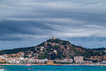Blanes Castle, from the beach, with clouds threatening rain