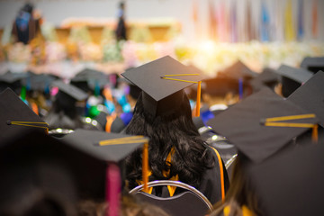 Soft selective focus rear view of the graduates in the graduation commencement ceremony receiving...