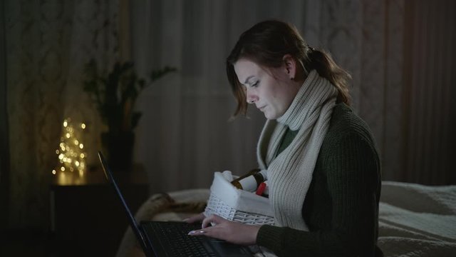 doctor online, a sick woman suffering from sore throat consults with a doctor about choice of medications while sitting on the bed with a laptop in bedroom
