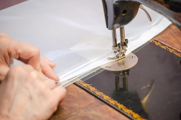 Hands of a woman who sews on an old sewing machine close up