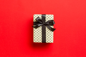 Top view Christmas present box with black bow on red background with copy space