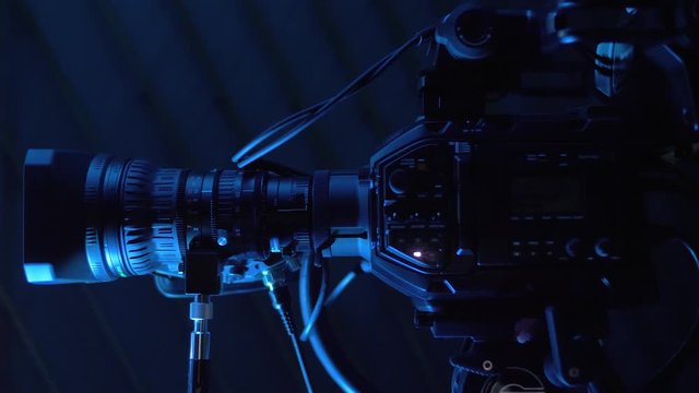 Professional camera with commutation equipment stands on tripod in news studio. Modern TV camera with many buttons and toggle switches for broadcasting or media production. Camera works live in studio
