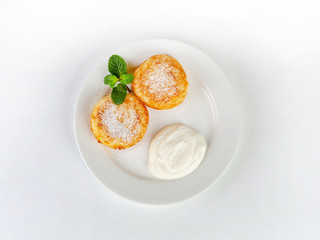 Cheesecakes with sour cream on a plate, decorated with mint leaves, top view