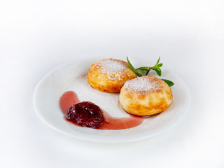 Cheesecakes with strawberry jam on a plate, decorated with mint leaves, side view