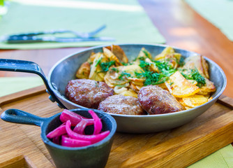 Cutlets with fried potatoes in a pan served on the table