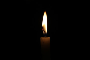 One light candle burning brightly in the black background