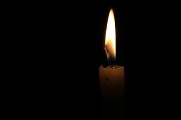 One light candle burning brightly in the black background