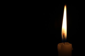 One light candle burning brightly in the black background