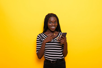 Young african american woman using smartphone standing over isolated yellow background