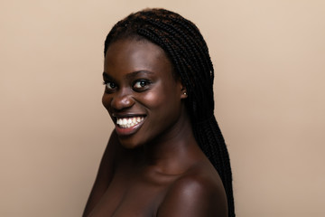 Portrait of a young beautiful african woman perfect skin isolated on beige. Skin care.