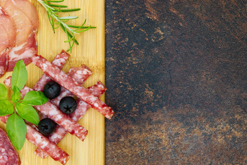 Meat and cheese plate antipasti snack with Prosciutto ham, Parmesan, Blue cheese, Cantaloupe melon and Olives on olive wood serving board on dark stone background