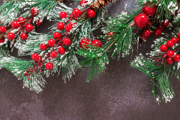 Christmas fir twigs with red berries and snowflakes on dark background