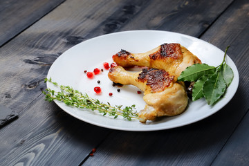 On a white dish on a dark wooden tabletop are two fried chicken
