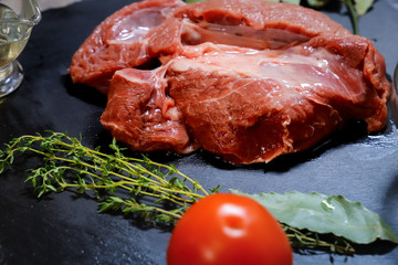 On a graphite-colored stone stand there is a piece of raw bright beef decorated with peas of peppers