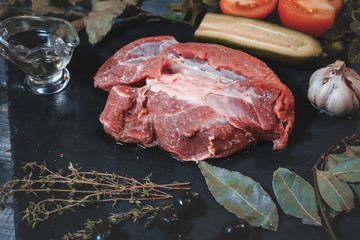 On a graphite-colored stone stand there is a piece of raw bright beef decorated with peas of peppers