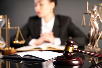 Young lawyer during work in chamber. Gavel, scale and Themis statue on the table.