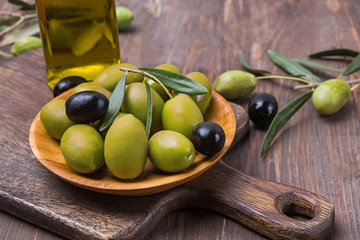 Green and black olives in small wooden plate