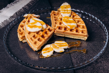 Waffles with bananas on a concrete gray background.